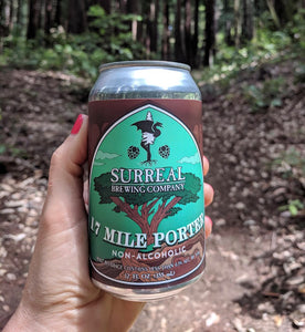 Can of Surreal Non-Alcoholic 17 Mile Porter being held in a hand in the forest setting.