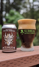 Load image into Gallery viewer, Can of Surreal Non-Alcoholic Pastry Porter on a fence next to a glass of Pastry Porter poured out. Dark color and large cream colored foam head. 
