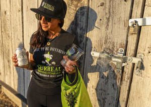 Woman with a Surreal Non-alcoholic beer, Surreal glass, branded hat, and dry bag.