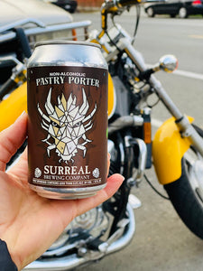 Can of Surreal Non-Alcoholic Pastry Porter next to a yellow colored motorcycle.