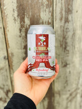 Load image into Gallery viewer, Can of Surreal Non-Alcoholic Red IPA being held near a fence.
