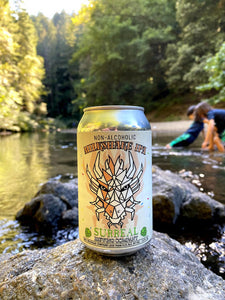 Can of Surreal NA Milkshake IPA. BAckground river with children playing.